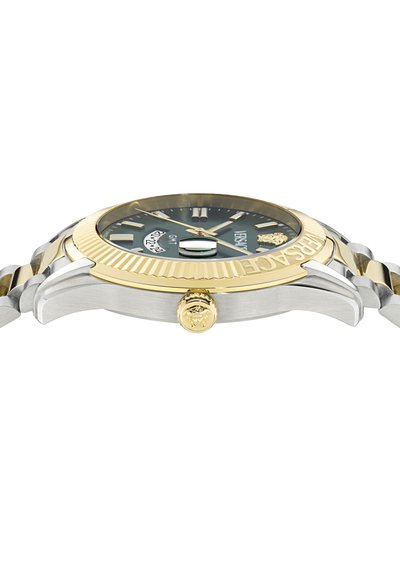 Ruostumattomasta teräksestä ja kultavärisistä yksityiskohdista valmistettu kello, jossa on vihreä kellotaulu, uritettu kehys ja leijonakuvioinen kruunu; päivämääränäyttö klo 3.