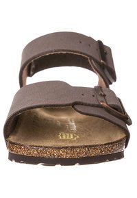 Sandale marron avec deux sangles réglables, semelle en liège et semelle extérieure en caoutchouc. Présente un dessus texturé et des boucles métalliques pour un ajustement sûr.