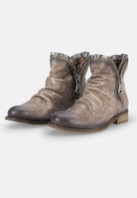 Bottes courtes en cuir beige avec un design perforé, des accents gris, une tige souple, des fermetures éclair argentées et un petit talon en bois.