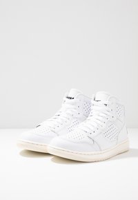 Sneaker alte in pelle bianca con dettagli perforati, punta rotonda, collarino imbottito e suola in gomma beige. Chiusura con lacci sul davanti.