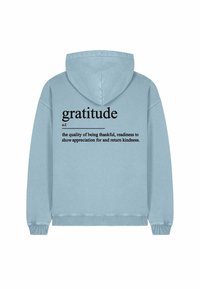 Kapuca sweatshirt, svetlo modra tkanina. Na hrbtni strani je v velikem črnem besedilu napisano "hvaležnost", pod tem pa je v manjšem besedilu definicija.