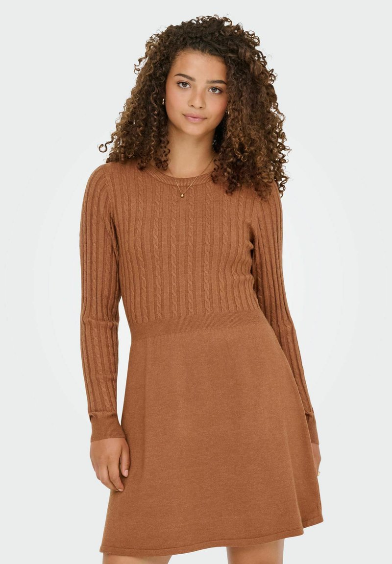 Rjava pletena obleka s rebrastim vzorcem na telu, dolgimi rokavi in razširjenim krilom. Preprosta okrogla izrezana ovratnica, obleka srednje dolžine.