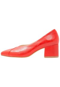 Rote Leder-Schuhe mit niedrigem Blockabsatz und spitzer Zehenform, präsentiert im Seitenprofil.