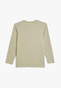 Pitkähihaisen vaaleanbeige puuvillapaidan pyöreä pääntie ja suora helma. Makuusammalta, ilman näkyviä kuvioita tai yksityiskohtia.