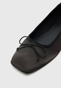 Μαύρο σατέν μπαλαρίνα με τετράγωνη μύτη, υφή στην επιφάνεια και μαύρο υφασμάτινο φιόγκο στο μπροστινό μέρος. Μαλακή εσω τερική επένδυση.