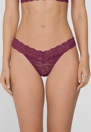 Koronkowy thong w głębokim purpurowym kolorze, z falbaniastym brzegiem, wzorami florystycznymi i delikatną fakturą. Elastyczny pas dla wygody.