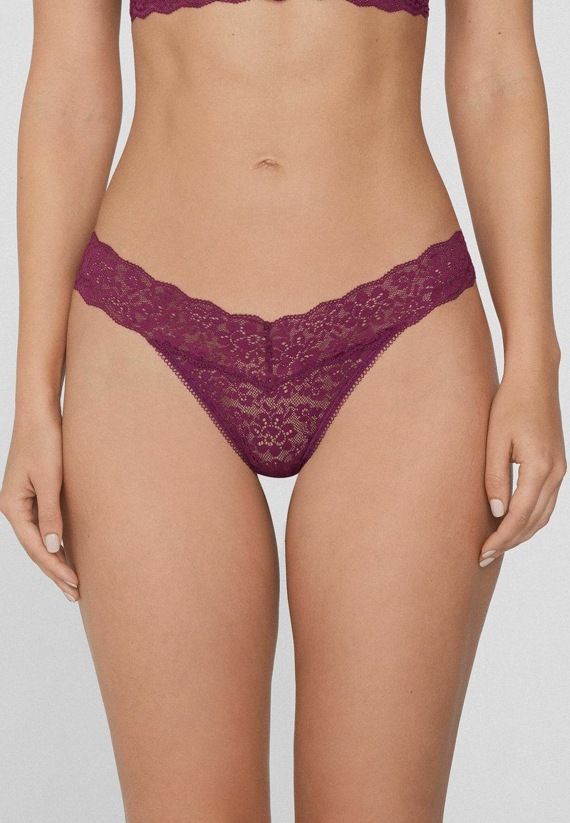 String en dentelle de couleur violet profond, avec une bordure à volants, des motifs floraux et une texture délicate. Ceinture élastique pour le confort.
