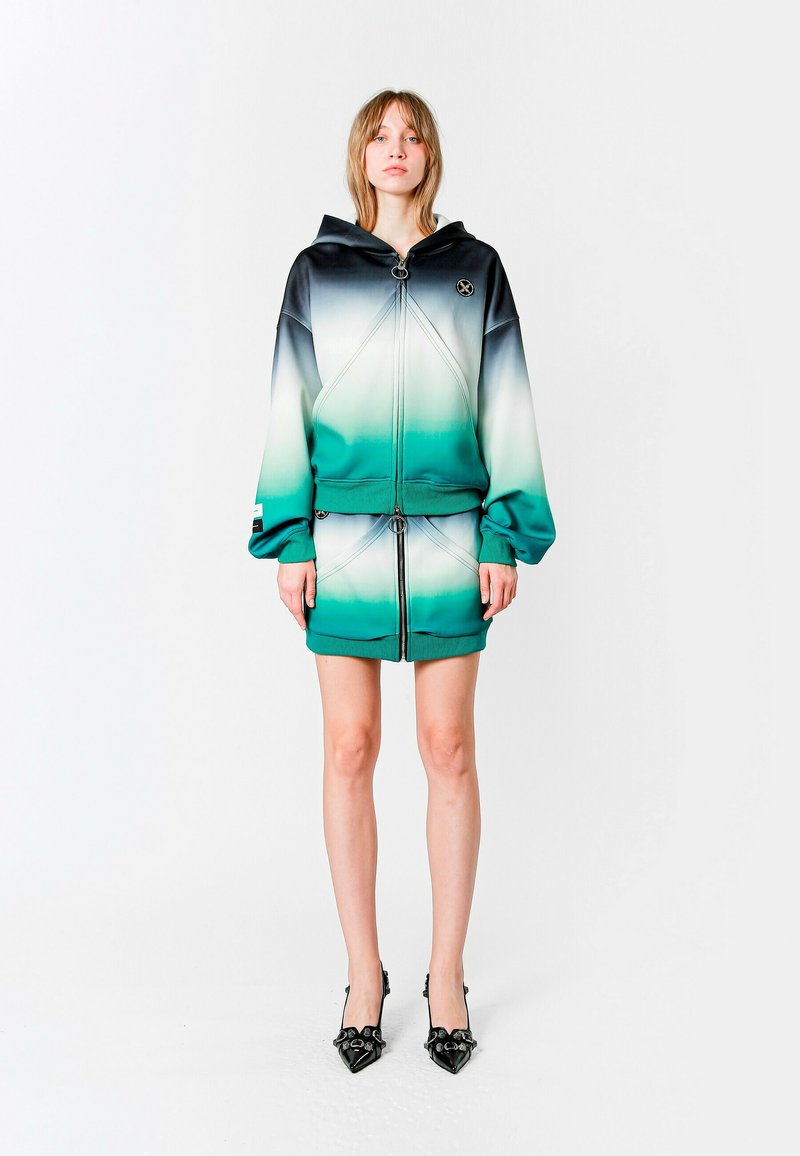 Conjunto de chaqueta con capucha y falda mini en una mezcla ombré de negro, verde y blanco. Presenta accesorios de metal, puños elásticos y un diseño deportivo.