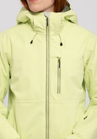 Hellgrüne wasserdichte Jacke mit Kapuze, durchgehendem Reißverschluss und Brusttasche; verfügt über verstellbare Zugbänder und Reißverschlussdetails.