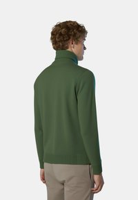 Maglione verde a collo alto realizzato in morbido tessuto a maglia, con collo e orlo a coste, visto da dietro su uno sfondo uniforme.