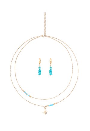 Delicata collana a strati in oro con piccole perline turchesi e pendente a stella, abbinata a orecchini a cerchio in oro con pietre turchesi pendenti.