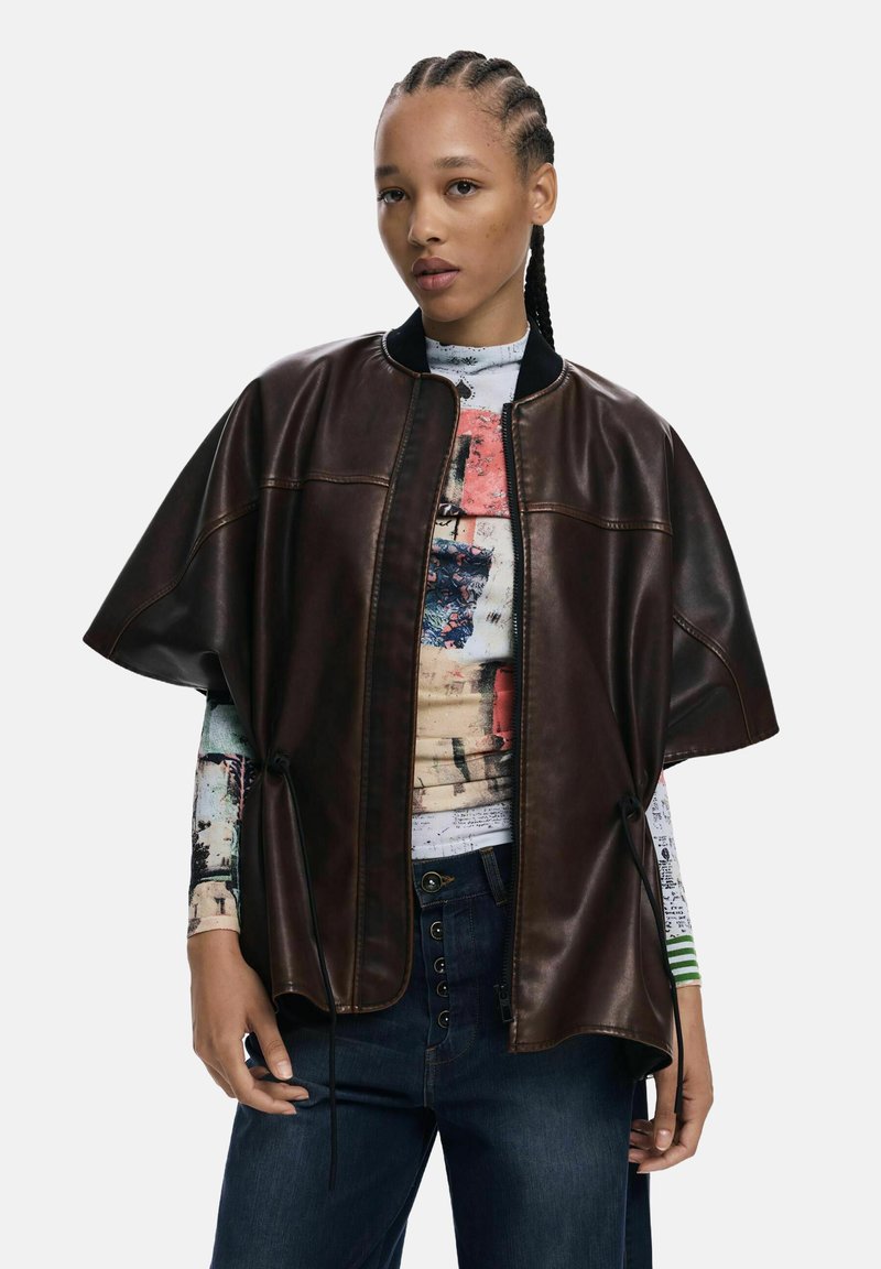 Brun läder poncho-stil jacka med dragkedja fram, ribbad krage och dragsko detaljer; bärs över en flerfärgad grafisk långärmad skjorta.