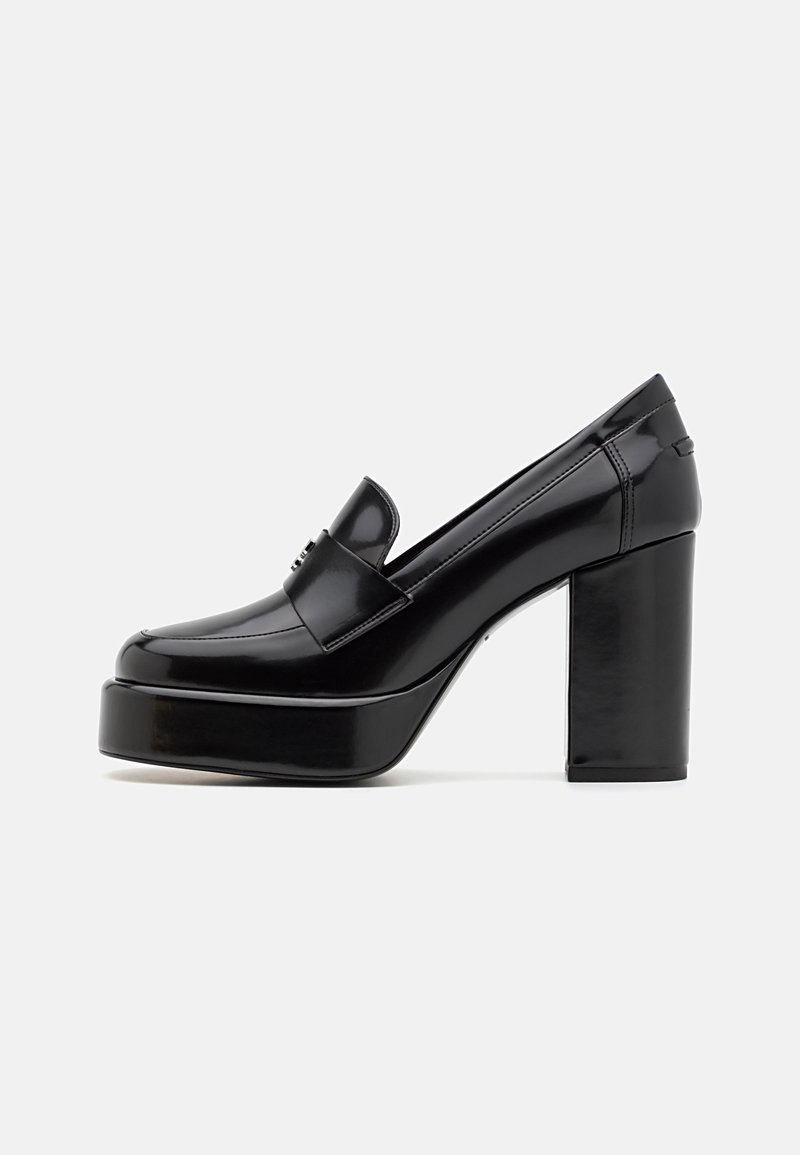 Mocassin à plateforme en cuir verni noir avec talon bloc épais et couture minimale, vu de côté sur fond blanc.