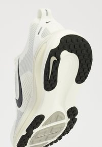High-top sneakers med en hvid mesh-overdel, sorte accenter og en struktureret gummisål med synligt mønster og Nike-logo.