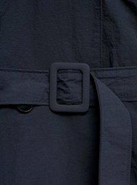 Temno modri tekstilni pas s kvadratno zaponko. Material izgleda teksturiran z vidnim šivom in gumbom, ki je blizu pasu.