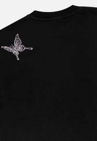Black cotton t-shirt featuring a crystal-embellished butterfly design on the back shoulder area. Short sleeves and crew neck style.