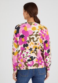 Pull côtelé à motif floral multicolore comprenant des teintes de rose, jaune et vert, avec une coupe décontractée et un col rond.