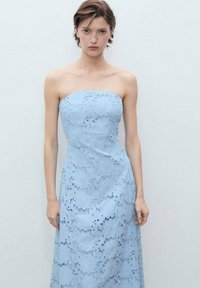Šaty bez ramienok v svetlomodrej lace farbe s kvetinovými výrezmi a priliehavým živôtikom, ktorý prechádza do dlhej, elegantnej sukne. Mäkka textura.
