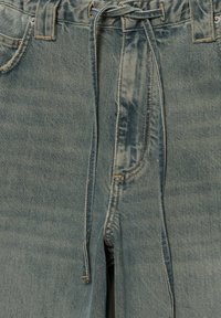 Lichtblauwe spijkerbroek met een taillekoord, voorzakken en een licht versleten textuur met zichtbare stiksel details.