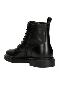 Stivale alla caviglia in pelle nera con texture liscia, cerniera laterale, lacci frontali e una robusta suola in gomma nera. Caratterizzato da una punta rotonda e un tassello sul tallone.