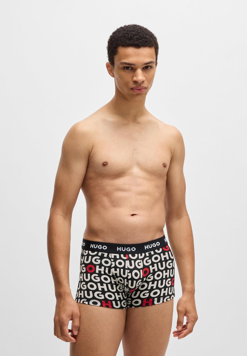 Boxer briefs pretos com impressão do logótipo "HUGO" em branco e vermelho, cintura elástica, ajuste justo e textura de tecido suave.