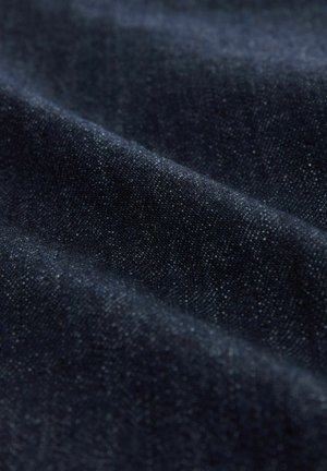 Dark denim fabric showcasing a smooth texture with subtle white flecks. The material is folded, highlighting its weight and thickness.