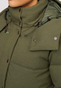 Grüne gepolsterte Jacke mit hohem Kragen, ausgestattet mit verstellbaren Zugbändern, Druckknöpfen und glattem Stoffgefühl.