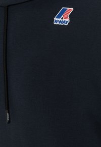 Felpa con cappuccio blu navy realizzata in tessuto liscio, con logo K-Way in rosso e blu. Include una cerniera nera con un tirazip personalizzato.