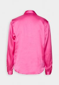 Chemise en satin rose vif à manches longues avec col, vue de dos, sur un fond uni gris clair.