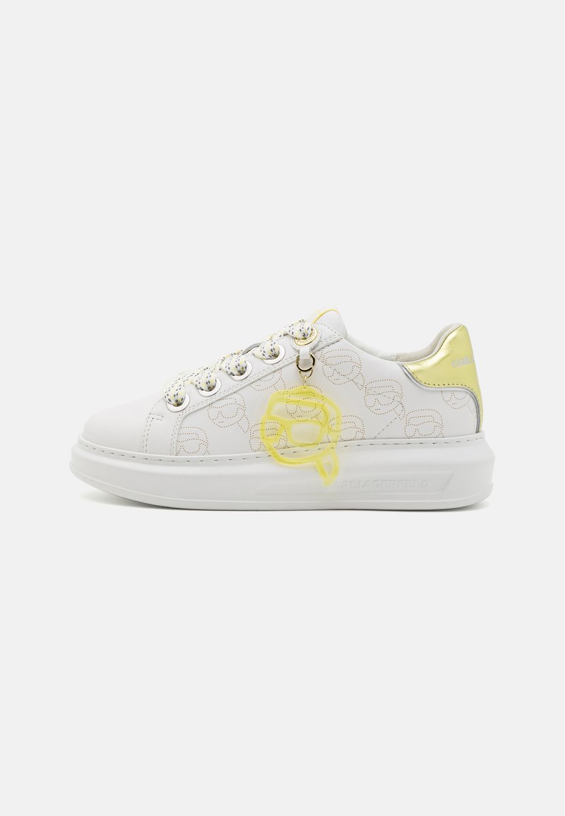 White sneaker with smooth leather, gold accents, and colorful logo charm. Features circular pattern and textured sole for grip.