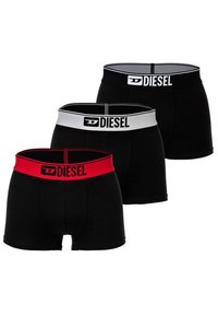 Trois paires de shorts boxers noirs avec des ceintures élastiques ; une avec une ceinture rouge, une avec une ceinture grise et une avec une ceinture noire.