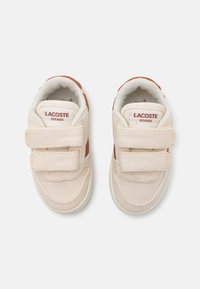 Sneakers in tessuto beige con due fasce in velcro, caratterizzati da dettagli marroni e un interno imbottito. Etichetta con logo sulla linguetta. Design con punta rotonda.