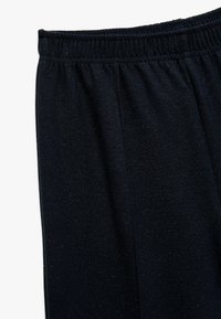Sorte strikbukser med elastisk talje og subtile teksturer. Overfladen har et let meleret mønster.