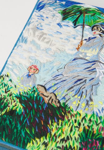 Femeie ținând o umbrelă verde, îmbrăcată într-o rochie albastră, cu un copil purtând o pălărie și un câine printre iarbă colorată, sub un cer nublat, brodat pe țesătură.