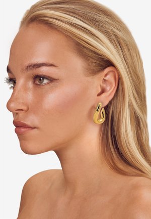 Goldene Metallohrringe mit einer fließenden, tropfenförmigen Gestalt. Glatte Textur mit glänzendem Finish, ausgestattet mit einem sicheren Postverschluss zum Tragen.