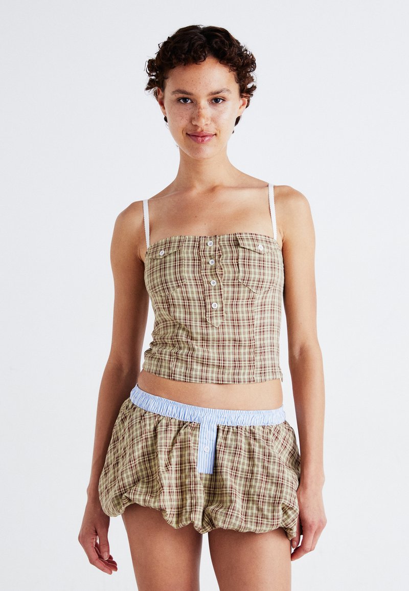 Brown and cream plaid cropped top with thin straps, featuring front buttons. Paired with matching voluminous shorts and a light blue elastic waistband.
