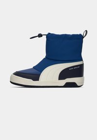 Botte bleue et marine déperlant avec un upper rembourré, une fermeture élastique et une semelle en caoutchouc épaisse. Présente un design à rayures de couleur claire.