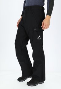 Zwarte outdoorbroek met cargozakken, versterkte naden, verstelbare tailleband en logodetail. Gemaakt van duurzaam, weerbestendig materiaal.