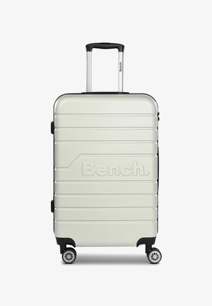 Valise rigide avec une finition gris clair brillante, des accents noirs, une surface texturée, des rainures horizontales et des doubles roues pour la mobilité.