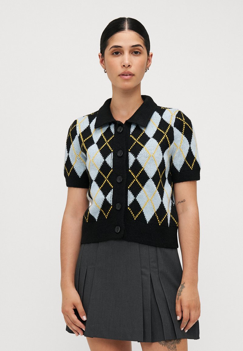 Černý a světle modrý cardigan s krátkým rukávem ve vzoru argyle s žlutými akcenty a pěti černými knoflíky, disponující límcem a přiléhavým střihem.