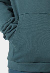 Miękka, turkusowa bluza z kapturem, z kieszenią typu kangur i ściągaczami przy rękawach. Gładka tekstura z detalami w szwach.