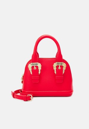 Sac à main en cuir rouge avec détails en tête de lion dorée, double poignées et une bandoulière amovible. Forme arrondie avec une finition texturée.