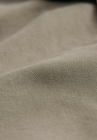 Beige woven fabric with a fine, textured surface; soft feel and slight sheen create a subtle, intricate pattern across the material.