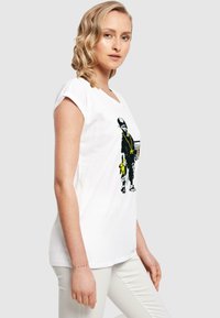 White cotton t-shirt featuring a graphic of a child in dark clothing with yellow accents. The design includes unique textures and bold colors.