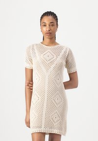 Knit dress featuring an openwork pattern with diamond shapes, short sleeves, and a rounded neckline in an off-white color.
