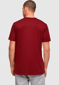 Bordeaux farvet bomulds T-shirt med korte ærmer, rund hals og et enkelt design. Stoffet virker blødt og let.