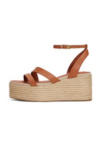 Brown leather wedge sandals with a braided jute platform, featuring wide cross straps and an ankle strap with a gold buckle accent.