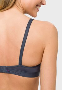 Dark navy bra with adjustable straps and a smooth texture. Features a hook-and-eye closure and "BeeDees" logo stitched on the band.