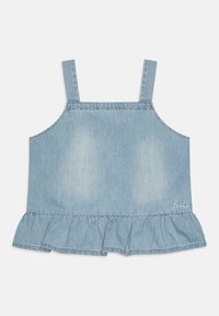 Ljusblå denimtop med justerbara axelband, volangnederkant och broderad logga i nedre högra hörnet. Slät textur, avslappnad design.
