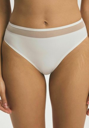 Žena nosiaca biele bikiny s priesvitným sieťovaným pásom, stojaca na neutrálnom pozadí.